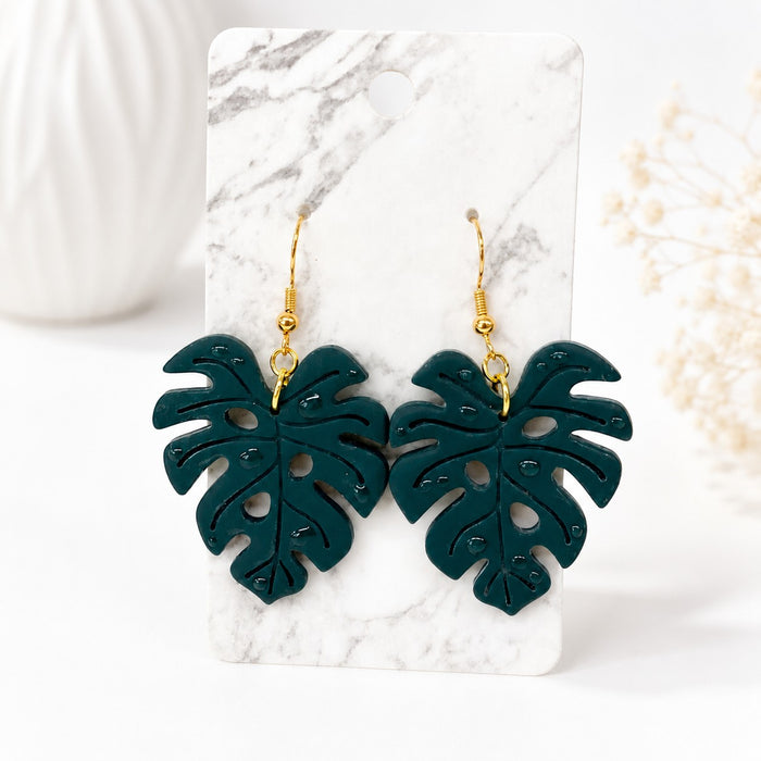Tea-Shirt Shoppe Palm & Petal Collection dark green monstera leaf dangle earrings with gold hooks on marble card